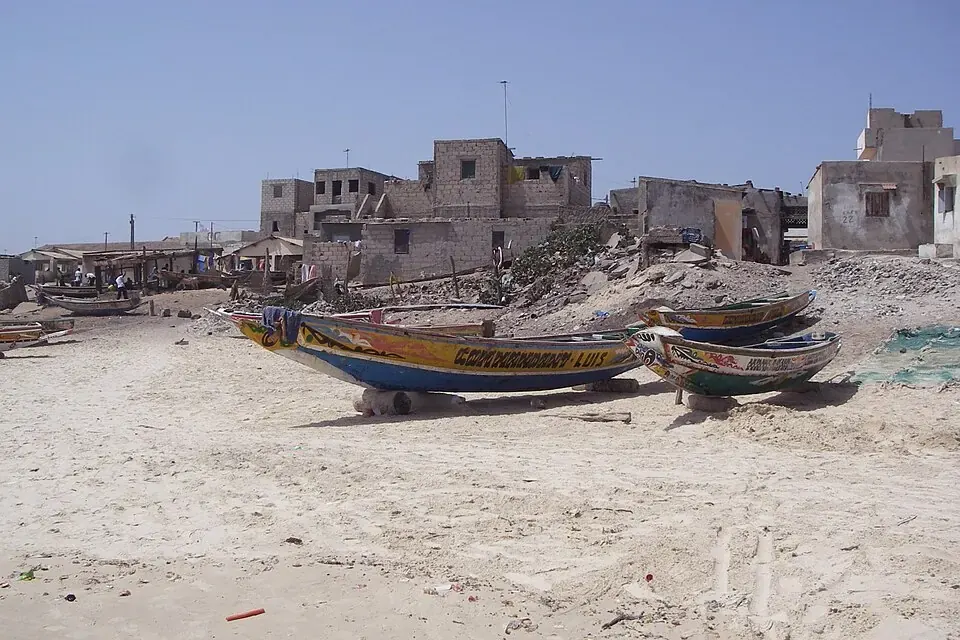 Pirogues de pêche colorées alignées sur la plage de Yoff, avec les immeubles de Dakar en arrière-plan